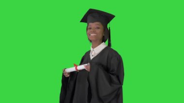 Mezuniyet cüppeli gülümseyen Afrikalı Amerikalı kız öğrenci Yeşil Ekran 'da diplomayla poz veriyor, Chroma Key.