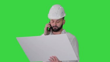 Formalite ve başlık mühendisi cep telefonundan müşteri ya da müteahhitle konuşuyor ve yeşil ekran, Chroma Key 'in planına bakıyor..