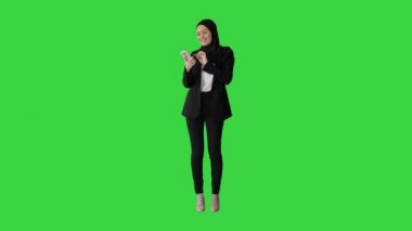 Türbanlı Müslüman kız, yeşil ekran, Chroma Key 'de sesli mesaj göndermek için akıllı telefon kullanıyor..