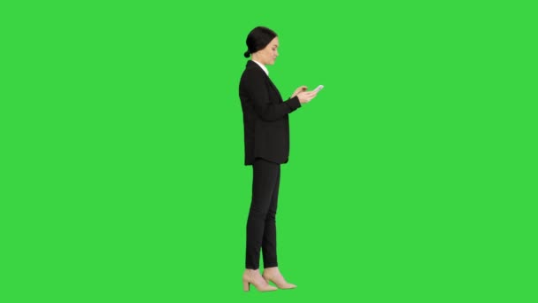 Nenucená žena v obleku textuje na svém telefonu na zelené obrazovce, Chroma Key. — Stock video