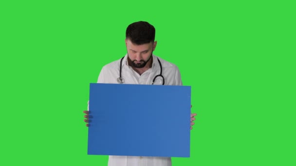 Az orvos egy üres panelt tart a zöld képernyőn, Chroma Key. — Stock videók