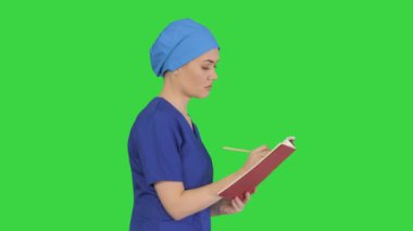Profesyonel kadın doktor eli, yeşil ekranda yürürken tıp dergisine notlar yazıyor, Chroma Key..