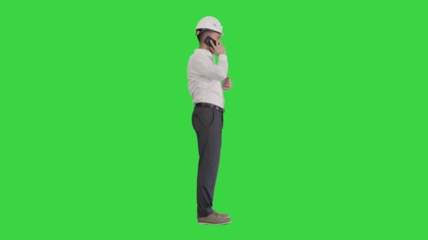 Ingenieur mit weißer Mütze im Gespräch mit seinem Handy auf einem Green Screen, Chroma Key. — Stockvideo