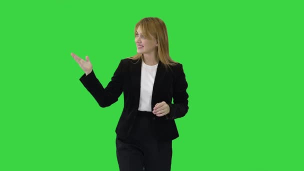 Женщина-ведущая блондинка, идущая и указывающая на боковые стороны на зеленом экране, Chroma Key. — стоковое видео