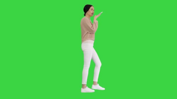 Mujer joven hablando por teléfono sosteniéndolo en su cara mientras camina en una pantalla verde, Chroma Key. — Vídeos de Stock