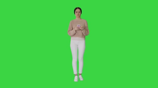 Menina morena encantadora com telefone em suas mãos esperando em uma tela verde, Chroma Key . — Vídeo de Stock