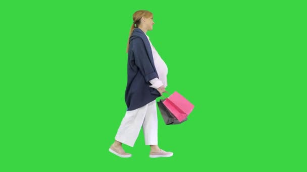 Vacker glad gravid kvinna promenader efter shopping på en grön skärm, Chroma Key. — Stockvideo