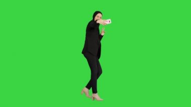 Yeşil Ekran 'da yürürken cep telefonuyla selfie çeken tesettürlü gülümseyen Arap kadın, Chroma Key.
