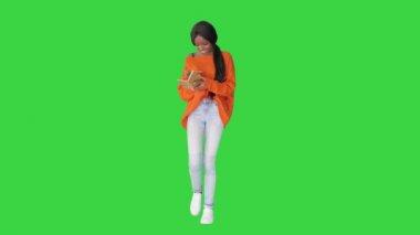Güzel Afro-Amerikan kadın, parlak kazaklı, not defterini okuyor ve yeşil ekranda gülüyor, Chroma Key..