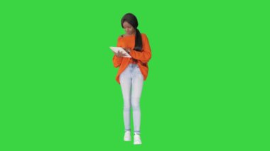 Gülümseyen Afrikalı Amerikalı kadın yeşil ekranda yürürken tablet kullanıyor, Chroma Key.