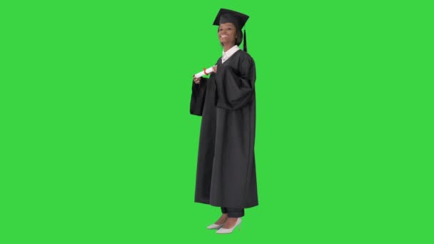 Χαμογελώντας Αφρο-Αμερικανίδα φοιτήτρια με στολή αποφοίτησης ποζάροντας με δίπλωμα σε πράσινη οθόνη, Chroma Key. — Αρχείο Βίντεο