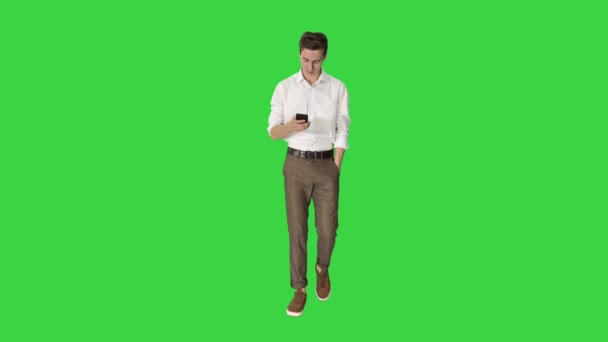 Молодой и привлекательный фрилансер ходит и использует свой телефон на зеленом экране, Chroma Key. — стоковое видео