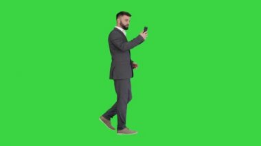 Yakışıklı iş adamı yeşil ekran, Chroma Key 'de telefonuyla yürüyor ve video kaydediyor..