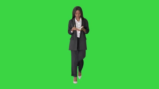 Jolie jeune femme noire écrivant dans un bloc-notes sur un écran vert, Chroma Key.