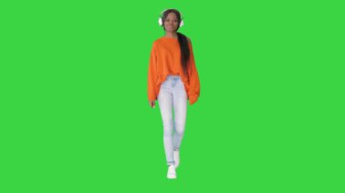 Gülümseyen Afro-Amerikalı kulaklıklı kadın yeşil ekran Chroma Key 'de müzik dinliyor..