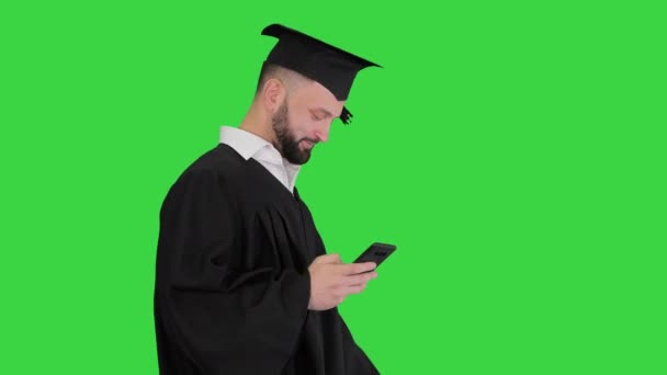 Végzős diák séta és SMS-t a telefonon egy zöld képernyőn, Chroma Key. — Stock videók