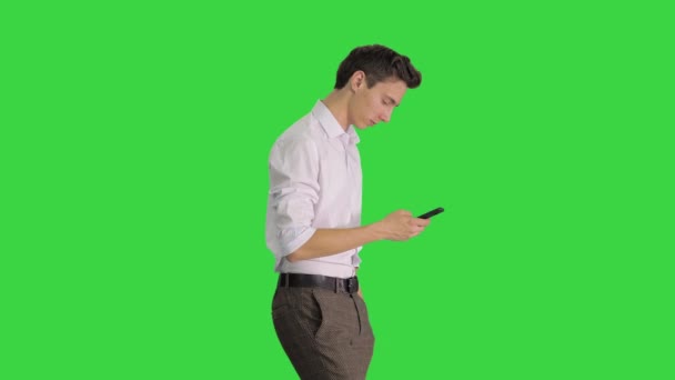 Man in wit shirt loopt met behulp van mobiele telefoon op een groen scherm, Chroma Key. — Stockvideo