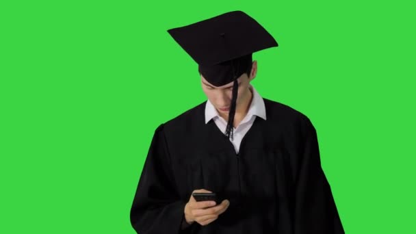 Végzős diák séta kéz sms üzenetet a telefonon egy zöld képernyőn, Chroma Key. — Stock videók
