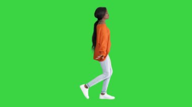Rahat, Afro-Amerikalı, parlak günlük kıyafetler giymiş genç bir kadın yeşil ekranda yürürken dans ediyor, Chroma Key.