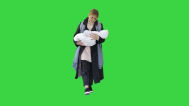 Anne elinde bebekle yeşil ekranda yürüyor, Chroma Key..