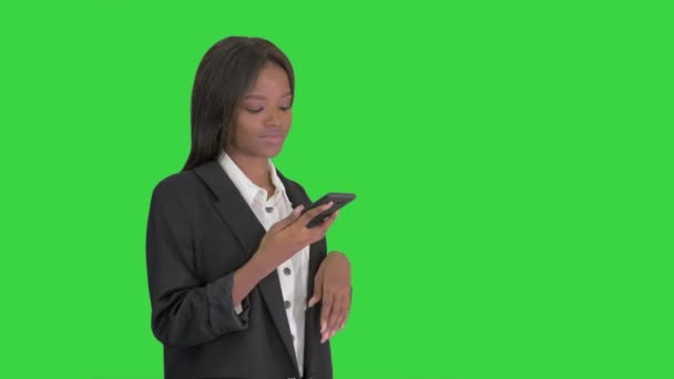 Lächelnde schwarze Frau beim SMS-Schreiben auf ihrem Handy auf einem grünen Bildschirm, Chroma Key. — Stockvideo