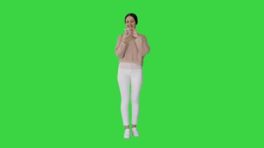 Kafası karışmış genç bir kadın, yeşil ekranda karışık duygularla akıllı telefon kullanıyor, Chroma Key..
