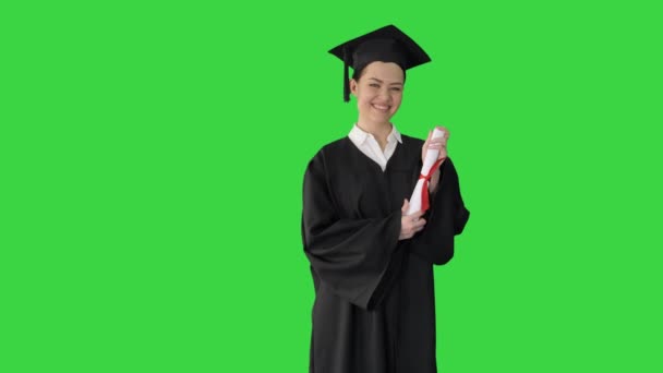 Mezuniyet cüppeli gülümseyen bayan öğrenci yeşil ekranda diplomasıyla poz veriyor, Chroma Key. — Stok video