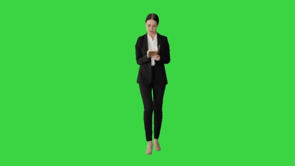 Концентрированная женщина в костюме, пишущая бизнес-идеи в блокноте во время прогулки по зеленому экрану, Chroma Key. — стоковое видео