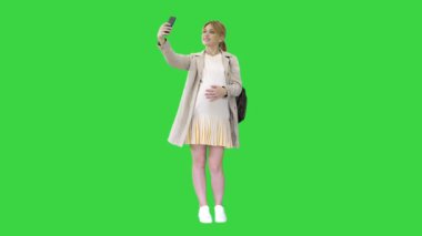 Mutlu genç hamile kadın yeşil ekranda selfie çekiyor, Chroma Key.