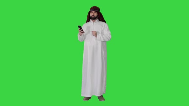 Araber mit seinem Smartphone im Internet surfen oder Nachrichten auf einem grünen Bildschirm, Chroma Key. — Stockvideo