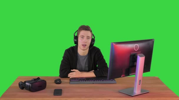 Junger Mann im Headset hält eine Rede vor der Kamera auf einem Green Screen, Chroma Key. — Stockvideo