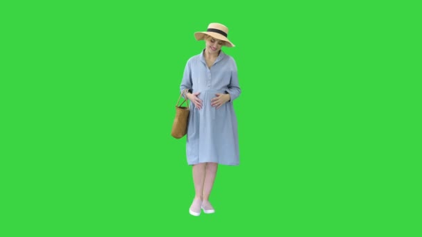 Hermosa mujer embarazada con sombrero grande caminando y tocando su vientre en una pantalla verde, Chroma Key. — Vídeo de stock