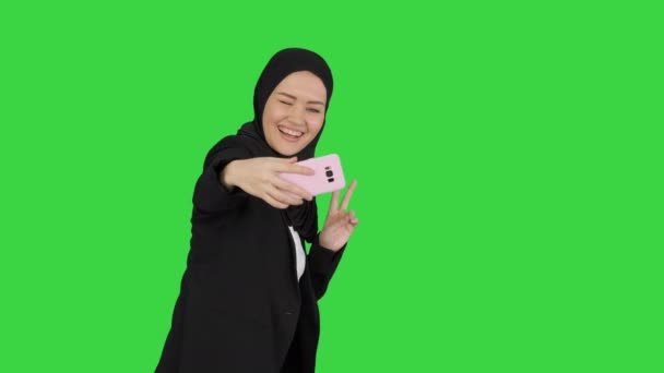 Sorridente donna araba in hijab scattare selfie sul suo telefono cellulare mentre cammina su uno schermo verde, Chroma Key. — Video Stock