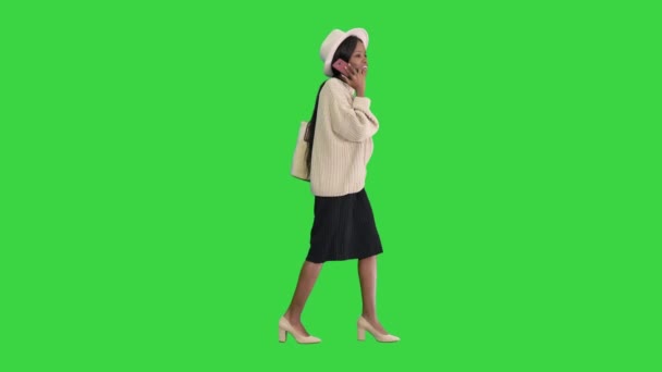 Frustrovaná africká americká žena v pleteném svetru a bílém klobouku mluví na telefonu na zelené obrazovce, Chroma Key. — Stock video