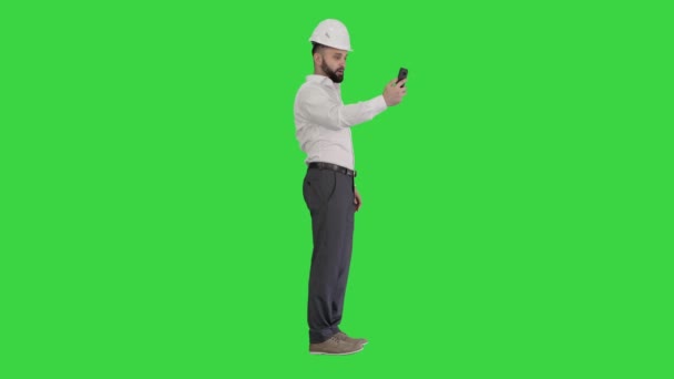 Uomo ingegnere indossa protezione casco di sicurezza e camicia fare videochiamate su uno schermo verde, Chroma Key. — Video Stock