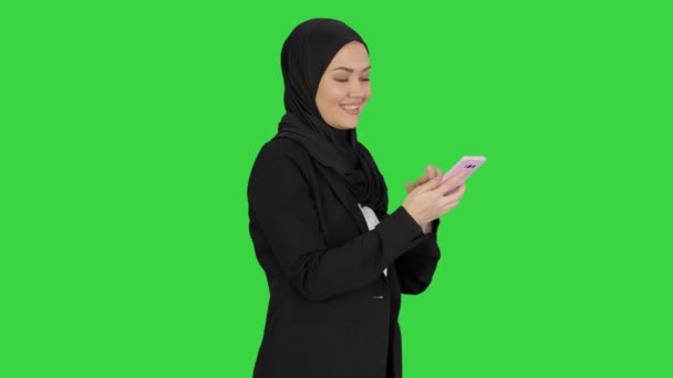 Moslim meisje in hijab met behulp van smartphone om spraakberichten te sturen op een groen scherm, Chroma Key. — Stockvideo