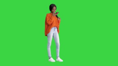 Güzel Afrikalı Amerikalı kadın. Parlak Jumper 'lı. Telefonunu Chroma Key' de Yeşil Ekran 'da kullanıyor..
