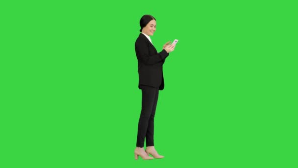 Mujer de negocios sonriente revisando fotos en su teléfono en una pantalla verde, Chroma Key. — Vídeo de stock