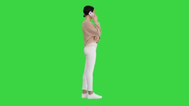 Duygusal gülümseyen genç bir kadın telefonda konuşuyor ve yeşil ekranda işaret ediyor, Chroma Key.