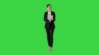 Gülümseyen iş kadını, yeşil ekranda kameraya doğru yürürken bilgisayarını kullanıyor, Chroma Key.