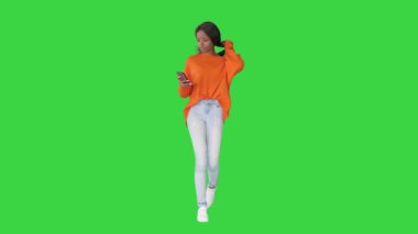 Gülümseyen kadın yeşil ekranda yürürken telefonuna mesaj yazıyor, Chroma Key.