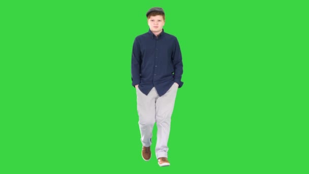 Fashionabla ung man går med händerna i fickor på en grön skärm, Chroma Key. — Stockvideo