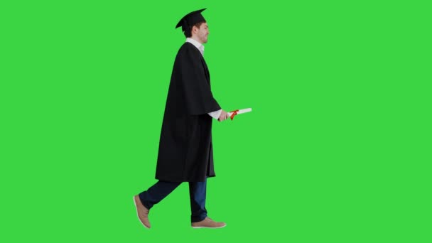 Felice studente maschio in vestaglia laurea a piedi e baciare il suo diploma su uno schermo verde, Chroma Key. — Video Stock