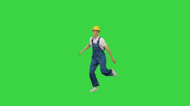 Mladý stavební pracovník ve žlutém hardhat break tanec při pohledu na kameru na zelené obrazovce, Chroma Key. — Stock video