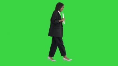 Ciddi bir Afrikalı Amerikalı kadın yeşil ekranda yürürken belge okuyor, Chroma Key.