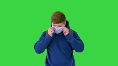 Genç bir çocuk okula yeşil ekranda, Chroma Key 'de tıbbi maske takarak gidiyor..