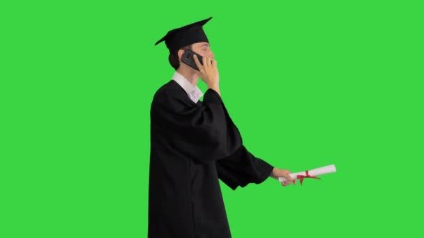Yüksek lisans öğrencisi akıllı telefondan konuşuyor ve yeşil ekranda yürüyor, Chroma Key. — Stok video