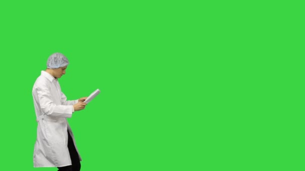 Троє лікарів чоловічої статі в білому одязі і захисних шапках, що проходять по документах, танцюючи рядами на зеленому екрані, Chroma Key. — стокове відео