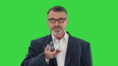 Takım elbiseli olgun bir adam yeşil ekranda viski ya da konyak içiyor, Chroma Key.