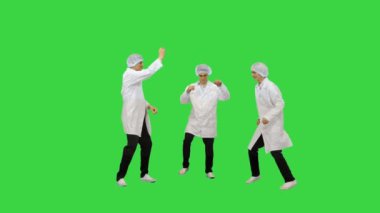 Beyaz cüppeli ve koruyucu şapkalı üç erkek doktor Yeşil Ekran 'da komik bir kutlama dansı yapıyorlar..